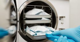 Young male dentist places medical autoclave for sterilising surgical and other instruments